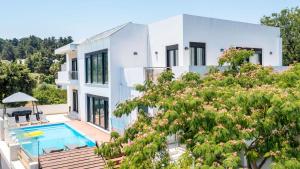a white house with a swimming pool and trees at Villa Melia in Koskinou