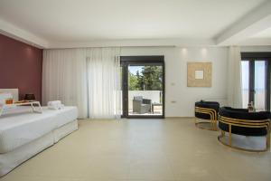 a bedroom with a bed and chairs and a window at Villa Melia in Koskinou +57 photos