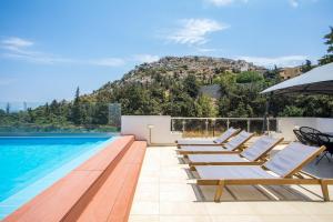 a swimming pool with lounge chairs and an umbrella at Villa Melia in Koskinou