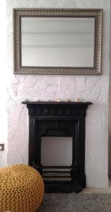 a mirror over a fireplace in a room with a chair at Cornish Cottage in Downalong, St Ives in St Ives