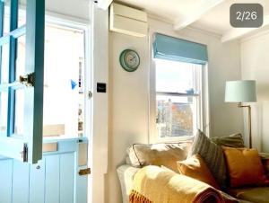 a living room with a couch and a clock on the wall at Cornish Cottage in Downalong, St Ives in St Ives