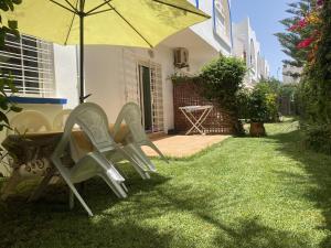 a table and chairs under an umbrella in a yard at calm and secure residence with pool in Sidi Bouzid
