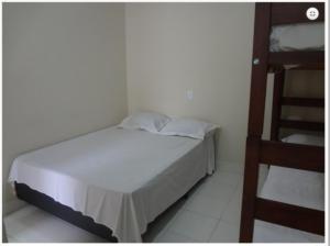 a white bed in a room with a ladder at Pousada PG One in Praia Grande