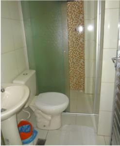 a bathroom with a shower and a toilet and a sink at Pousada PG One in Praia Grande