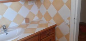a bathroom with a sink and a checkered wall at Chambre proche de paris et Roissy in Persan