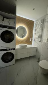 a bathroom with a sink and a washing machine at Nowoczesny Apartament Tatarska in Przemyśl +34 photos