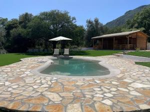 a small pool with two chairs and an umbrella at The Retreat - Oak Lodge in Corfu