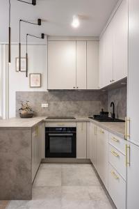 a kitchen with white cabinets and a stove top oven at Comfy Aparts Plac Solny II in Głogów