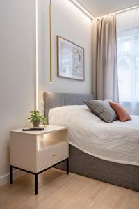 a bedroom with a bed with a night stand and a window at Comfy Aparts Plac Solny II in Głogów