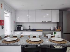 a kitchen with a table with white plates and chairs at Seventy House By Furabeach in Furadouro