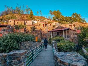 a woman walking down a wooden walkway in a village at Villa Boutique by O Cobra in Vila de Rei +36 photos