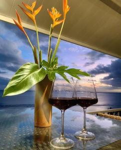 two glasses of wine and a vase with a plant at Villa Maui1 in Vaihi