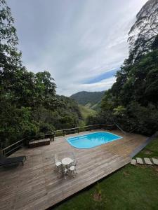 a swimming pool on a wooden deck with two chairs at Casinha do Fotógrafo em Domingos Martins a 7km do Centro in Domingos Martins