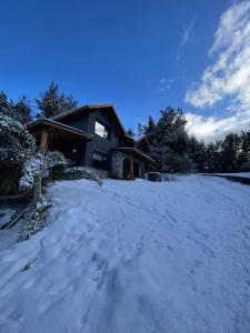 una casa con nieve delante en Tawa Wasi - Villa la Angostura, en Villa La Angostura