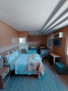 a hotel room with two beds and a television at Pousada Charme da Serra in Bom Jardim da Serra