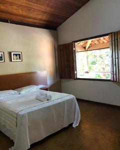 a bedroom with a bed and a large window at Pousada Matuto Cipó in Serra do Cipo