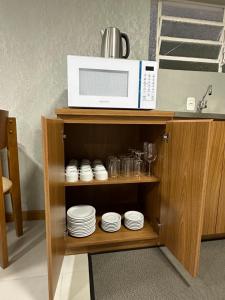 a microwave sitting on top of a shelf with plates at Casa Emma Gramado 4 in Gramado +7 photos