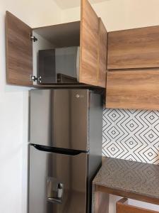 una nevera de acero inoxidable en una cocina con armarios de madera en Mako 235, en Tepic 14 fotos más