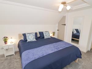 a bedroom with a blue bed and a mirror at The Cottage in Stratford-upon-Avon