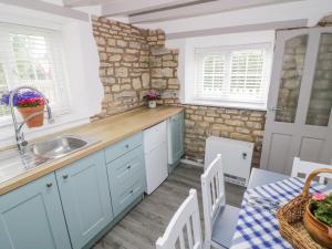 a kitchen with blue cabinets and a stone wall at The Cottage in Stratford-upon-Avon
