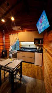 a kitchen with a table and a tv in a room at Cabana Alpen Ville com Banheira - Rural in Bom Jardim da Serra +45 photos