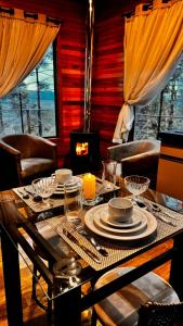 a dining room table with plates and glasses and a fireplace at Cabana Alpen Ville com Banheira - Rural in Bom Jardim da Serra