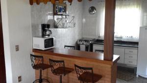 a kitchen with a counter with chairs and a microwave at Chalé de La Luna in Monte Verde
