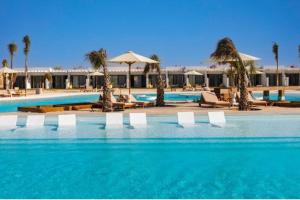a pool with chairs and umbrellas in a resort at D-bay North coast in Zāwiyat ‘Abd al Mun‘im