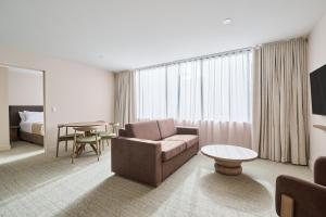 Habitación de hotel con sofá y mesa en Abode Phillip, en Canberra