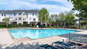 a large swimming pool with chairs and a building at New Intown Waterfront Townhome wPool & Location in Cambridge