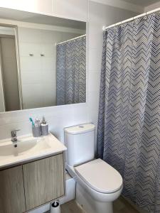 a bathroom with a toilet and a sink and a shower curtain at Depto en La Serena con vista al mar in La Serena