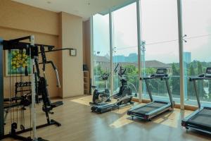 a gym with cardio equipment in a room with windows at Luxurious Studio at Capitol Suites Apartment By Travelio in Jakarta