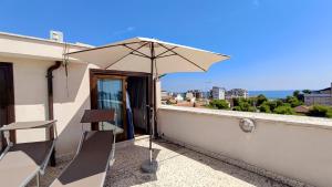 a patio with an umbrella and a chair at Attico Novecento in Porto San Giorgio