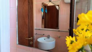 a bathroom with a sink and a mirror and flowers at Attico Novecento in Porto San Giorgio +13 photos