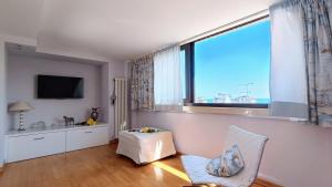 a living room with a large window and a chair at Attico Novecento in Porto San Giorgio