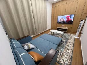 アジュマーンにあるElite Horizon Ajman Residenceの青いソファと薄型テレビのあるリビングルーム
