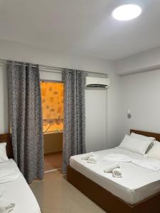 two beds in a room with a window at Joal Rooms in Sarandë +2 photos