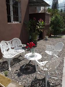 three white chairs and a table with a vase of flowers at bleesed House aeropuerto in Monte Adentro