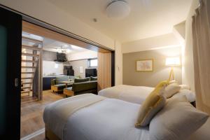 a hotel room with two beds and a living room at TAKUTO STAY SAKAISUJI-HOMMACHI in Osaka