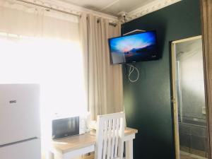 una camera con TV su un muro con sedia bianca di Mavi Guest house a East London