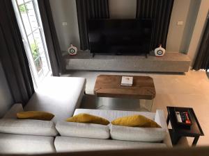 a living room with a white couch and a television at Grande Sun Seaside Villas Koh Chang in Ban Dan Kao