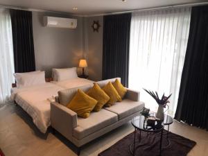 a bedroom with a bed and a couch with yellow pillows at Grande Sun Seaside Villas Koh Chang in Ban Dan Kao