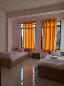 two beds in a room with orange curtains at THE LUSHAI INN in Āīzawl
