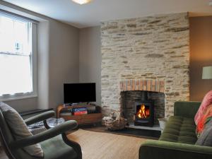 a living room with a fireplace and a tv at 2 Court Cottages in Kingsbridge