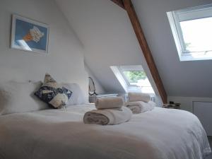 a bedroom with a white bed with towels on it at 2 Court Cottages in Kingsbridge