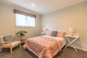 a bedroom with a bed and a chair and a window at Central Te Awamutu Modern House in Te Awamutu