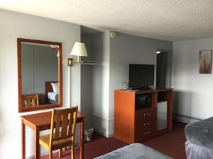 a hotel room with a desk and a bed and a mirror at Swiss Cottage Inn in Niagara Falls