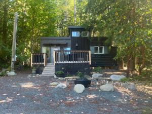 a cabin in the woods with a porch and some rocks at Malaspina Strait Tiny Home in Powell River