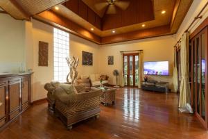 ein Wohnzimmer mit Möbeln und einem Flachbildfernseher in der Unterkunft V235 Huge Pool 4 Mins Kamala Beach 12 Mins Patong in Kamala Beach