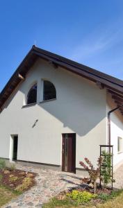 un edificio bianco con una porta e una finestra di Jeziorosfera. Stodoła przy wodzie. a Mrągowo